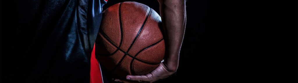 Close-up of a basketball being held by a player in dark attire