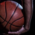 Close-up of a basketball being held by a player in dark attire
