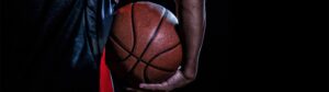 Close-up of a basketball being held by a player in dark attire