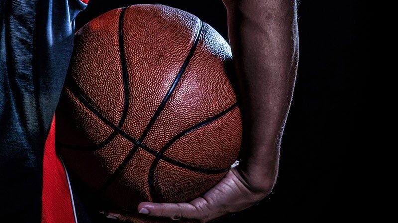 Close-up of a basketball being held by a player in dark attire